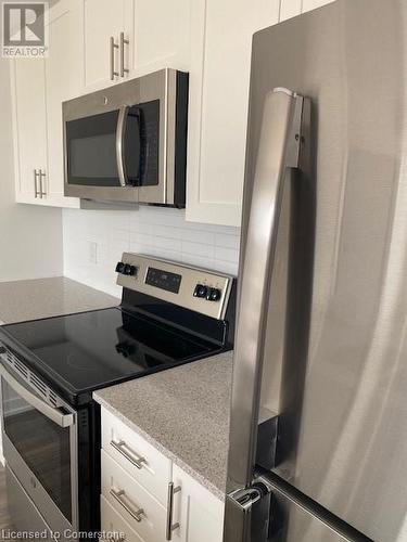 Kitchen with white cabinets, appliances with stainless steel finishes, and backsplash - 550 North Service Road Unit# 1001, Grimsby, ON - Indoor Photo Showing Kitchen