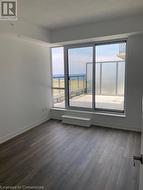 Spare room with a water view, dark wood-type flooring, and a textured ceiling - 