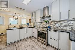 Kitchen with updated cabinetry, stainless steel stove, pendant lighting, and large sink. - 