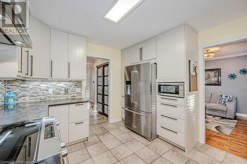 Kitchen featuring stainless steel appliances, white cabinetry, range hood, tile flooring, and decorative backsplash - 2378 Headon Road, Burlington, ON - Indoor Photo Showing Kitchen With Stainless Steel Kitchen