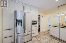 Kitchen featuring white cabinetry, stainless steel appliances, light tile patterned floors, and pendant lighting - 