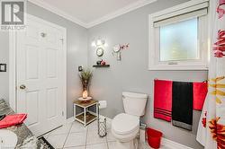 Bathroom with toilet, vanity, tile patterned flooring, and crown molding - 