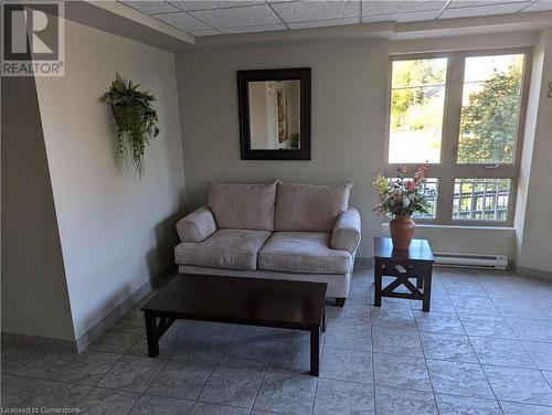 Living room featuring tile patterned flooring, a baseboard heating unit, and a drop ceiling - 56 Kerman Avenue Unit# 312, Grimsby, ON - Indoor Photo Showing Living Room