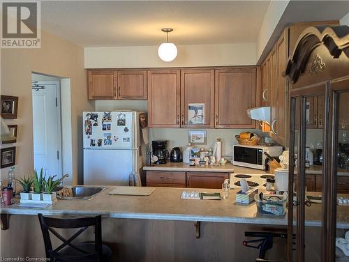 Kitchen featuring hanging light fixtures, sink, white appliances, and a breakfast bar - 56 Kerman Avenue Unit# 312, Grimsby, ON - Indoor Photo Showing Kitchen