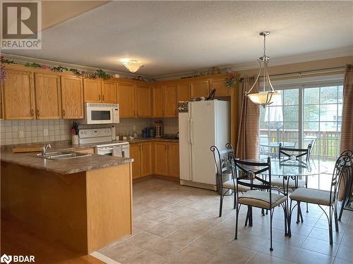 Kitchen featuring kitchen peninsula, light tile patterned floors, pendant lighting, sink, and white appliances - 316 Main Street W, Dundalk, ON - Indoor Photo Showing Kitchen With Double Sink