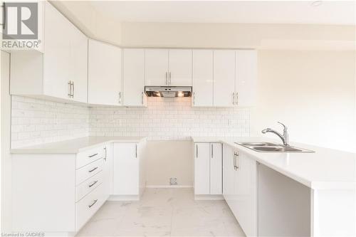 Kitchen featuring white cabinets, sink, and backsplash - 620 Colborne Street W Unit# 42, Brantford, ON - Indoor Photo Showing Kitchen With Double Sink