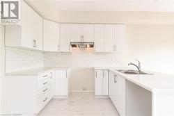 Kitchen featuring white cabinets, sink, and backsplash - 