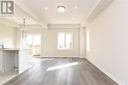 Unfurnished living room with beamed ceiling, a healthy amount of sunlight, sink, and light wood-type flooring - 