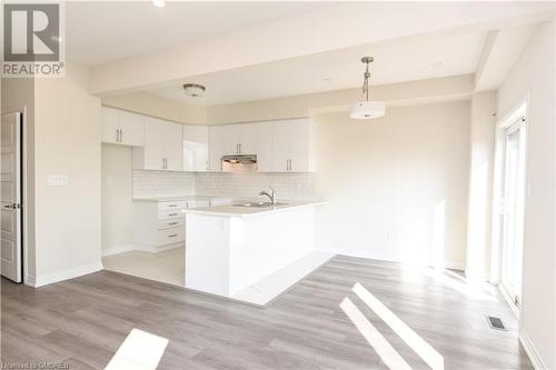 Kitchen with white cabinetry, pendant lighting, kitchen peninsula, and light hardwood / wood-style flooring - 620 Colborne Street W Unit# 42, Brantford, ON - Indoor Photo Showing Kitchen