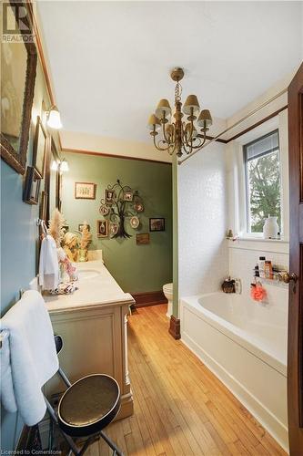 Bathroom featuring toilet, a notable chandelier, hardwood / wood-style flooring, vanity, and a bath - 687 Highway 6 Highway, Caledonia, ON - Indoor