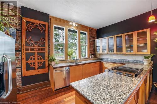 Kitchen with hanging light fixtures, light stone countertops, light hardwood / wood-style flooring, and appliances with stainless steel finishes - 687 Highway 6 Highway, Caledonia, ON - Indoor Photo Showing Kitchen With Double Sink