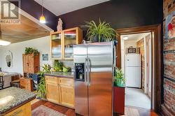 Kitchen with dark stone countertops, pendant lighting, white refrigerator, and stainless steel fridge - 