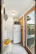 Kitchen featuring white cabinets, brick wall, and white refrigerator - 