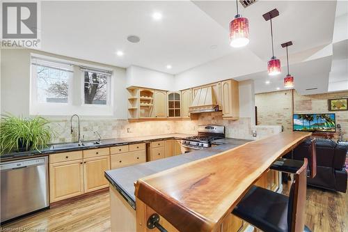 Kitchen with sink, custom range hood, light brown cabinets, light wood-type flooring, and appliances with stainless steel finishes - 687 Highway 6 Highway, Caledonia, ON - Indoor Photo Showing Kitchen With Double Sink