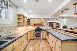 Kitchen featuring maple cabinets, pendant light fixtures, premium range hood, and stainless steel appliances - 