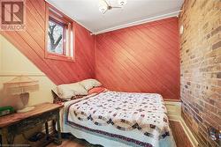 Bedroom featuring wood-type flooring, wooden walls, brick wall, and crown molding - 