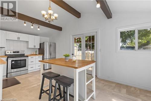 Kitchen featuring stainless steel appliances, white cabinetry, wooden counters, a breakfast bar area, and vaulted ceiling with beams - 233 Nile Street, Stratford, ON - Indoor Photo Showing Kitchen