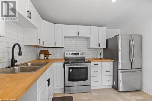 Kitchen featuring butcher block countertops, tasteful backsplash, white cabinets, and stainless steel appliances - 233 Nile Street, Stratford, ON - Indoor Photo Showing Kitchen With Double Sink