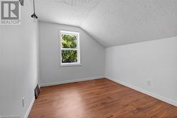 Additional living space featuring a textured ceiling, vaulted ceiling, and wood-type flooring - 