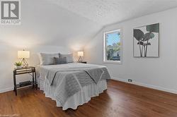 Bedroom featuring dark wood-type flooring, vaulted ceiling, and a textured ceiling - 