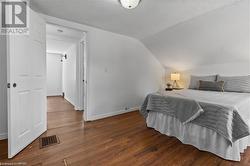 Bedroom featuring dark wood-type flooring, vaulted ceiling, and a textured ceiling - 