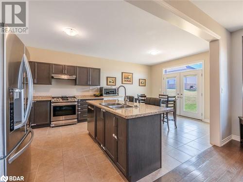 Kitchen featuring stainless steel appliances, dark brown cabinetry, sink, a kitchen island with sink, and light wood-type flooring - 3046 Stone Ridge Boulevard, Orillia, ON - Indoor Photo Showing Kitchen With Stainless Steel Kitchen With Double Sink