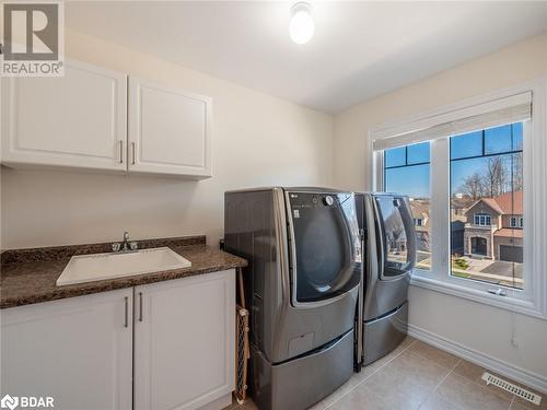 Laundry room with cabinets, light tile patterned floors, sink, and washer and dryer - 3046 Stone Ridge Boulevard, Orillia, ON - Indoor Photo Showing Laundry Room