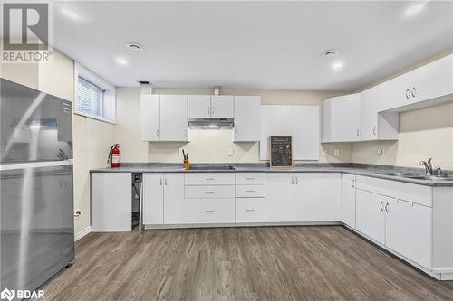 Kitchen with dark hardwood / wood-style flooring, sink, black stovetop, white cabinetry, and fridge - 3046 Stone Ridge Boulevard, Orillia, ON - Indoor Photo Showing Kitchen With Double Sink