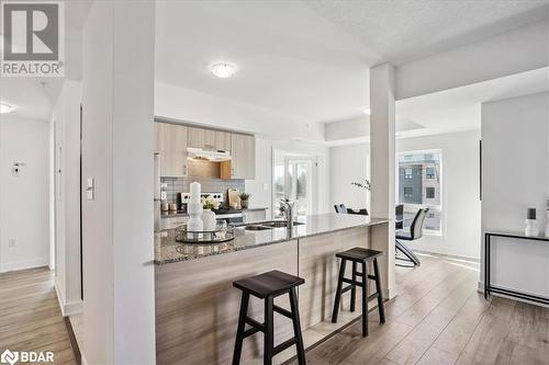 Kitchen with a kitchen bar, stone counters, sink, and a healthy amount of sunlight - 8 Culinary Lane Unit# 402, Barrie, ON - Indoor Photo Showing Other Room