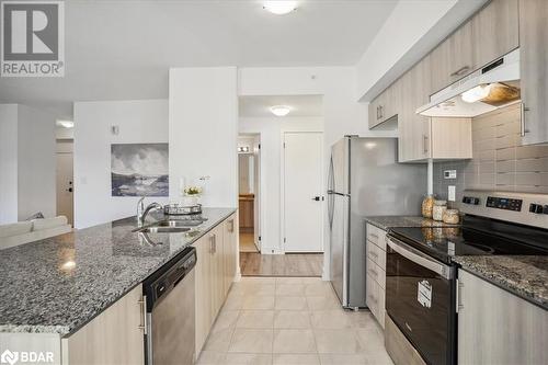 Kitchen featuring stainless steel appliances, light brown cabinetry, dark stone countertops, and sink - 8 Culinary Lane Unit# 402, Barrie, ON - Indoor Photo Showing Kitchen With Double Sink With Upgraded Kitchen