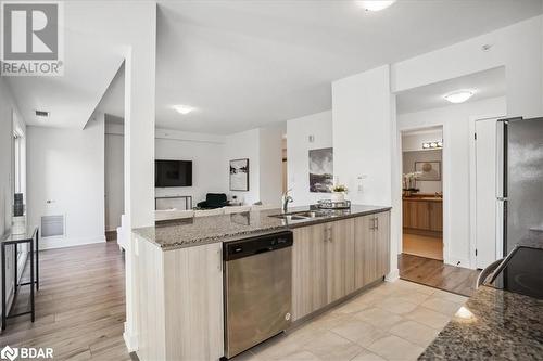 Kitchen with sink, appliances with stainless steel finishes, light brown cabinetry, dark stone countertops, and light wood-type flooring - 8 Culinary Lane Unit# 402, Barrie, ON - Indoor Photo Showing Kitchen With Double Sink