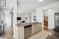 Kitchen with sink, appliances with stainless steel finishes, light brown cabinetry, dark stone countertops, and light wood-type flooring - 