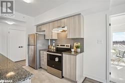 Kitchen featuring appliances with stainless steel finishes, light brown cabinetry, decorative backsplash, dark stone countertops, and light hardwood / wood-style flooring - 