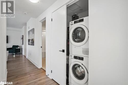 Clothes washing area featuring stacked washing maching and dryer and light hardwood / wood-style flooring - 8 Culinary Lane Unit# 402, Barrie, ON - Indoor Photo Showing Laundry Room