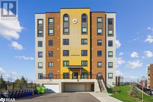 View of building exterior with a garage - 8 Culinary Lane Unit# 402, Barrie, ON - Outdoor With Facade