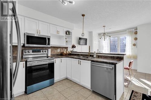 Kitchen featuring stainless steel appliances, white cabinets, pendant lighting, and a textured ceiling - 50 Howe Drive Unit# 17B, Kitchener, ON - Indoor Photo Showing Kitchen With Double Sink