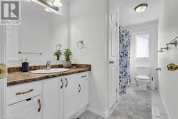 Bathroom with toilet, vanity, a textured ceiling, and tile patterned flooring - 