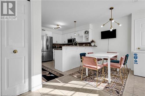 Kitchen with kitchen peninsula, appliances with stainless steel finishes, decorative backsplash, white cabinets, and a chandelier - 50 Howe Drive Unit# 17B, Kitchener, ON - Indoor