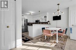 Kitchen with kitchen peninsula, appliances with stainless steel finishes, decorative backsplash, white cabinets, and a chandelier - 