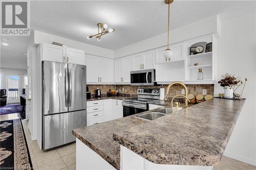 Kitchen featuring appliances with stainless steel finishes, pendant lighting, sink, white cabinets, and kitchen peninsula - 50 Howe Drive Unit# 17B, Kitchener, ON - Indoor Photo Showing Kitchen With Double Sink With Upgraded Kitchen