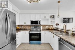 Kitchen featuring white cabinets, appliances with stainless steel finishes, sink, and hanging light fixtures - 