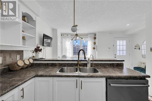 Kitchen featuring a textured ceiling, pendant lighting, sink, white cabinets, and dishwasher - 50 Howe Drive Unit# 17B, Kitchener, ON - Indoor Photo Showing Kitchen With Double Sink