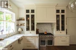 Kitchen with double oven range, sink, light stone counters, and decorative backsplash - 