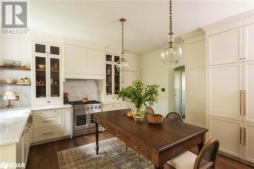 Kitchen featuring dark hardwood / wood-style flooring, light stone countertops, hanging light fixtures, decorative backsplash, and range with two ovens - 42 Burton Avenue, Barrie, ON - Indoor