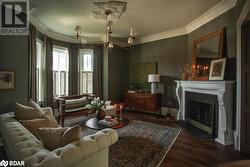 Living area featuring dark wood-type flooring, a chandelier, crown molding, and a fireplace - 