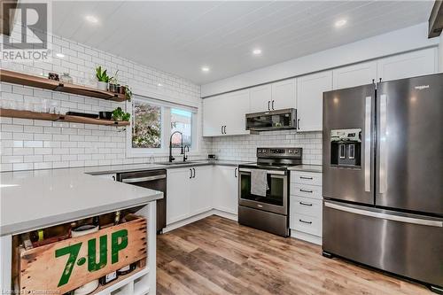 Kitchen featuring white cabinetry, sink, appliances with stainless steel finishes, light wood-type flooring, and decorative backsplash - 230 Blackhorne Drive Unit# 19, Kitchener, ON - Indoor Photo Showing Kitchen With Upgraded Kitchen