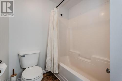 Bathroom featuring hardwood / wood-style floors, shower / bath combination with curtain, and toilet - 230 Blackhorne Drive Unit# 19, Kitchener, ON - Indoor Photo Showing Bathroom