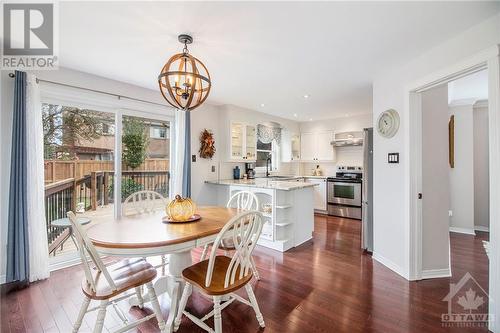 The modern, bright white kitchen features granite countertops, stainless steel appliances, a pantry, and a convenient eating area with a walk-out to the back deck - 807 Brissac Way, Ottawa, ON - Indoor Photo Showing Dining Room