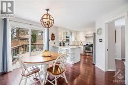 The modern, bright white kitchen features granite countertops, stainless steel appliances, a pantry, and a convenient eating area with a walk-out to the back deck - 