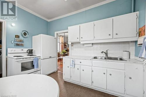 Kitchen with sink, dark hardwood / wood-style floors, backsplash, white cabinetry, and white appliances - 55 Edgehill Drive, Guelph, ON - Indoor Photo Showing Kitchen With Double Sink